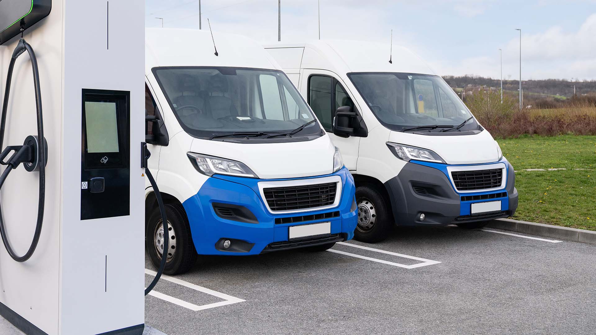 A small fleet of electric delivery vans at a charging station. A small fleet of electric delivery vans at a charging station.
