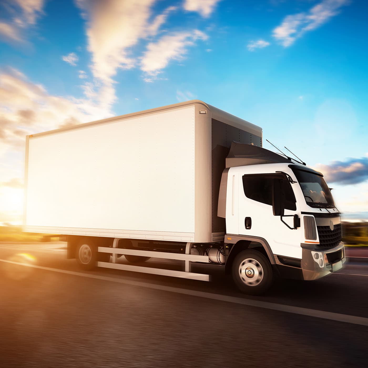 A truck driving on a road with blue skies and clouds above. A truck driving on a road with blue skies and clouds above.