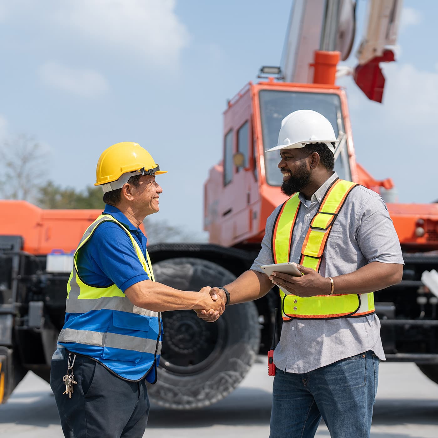 Male fleet consultant shaking hands with an engineer for agreement lease a mobile crane truck on a construction site. Male fleet consultant shaking hands with an engineer for agreement lease a mobile crane truck on a construction site.