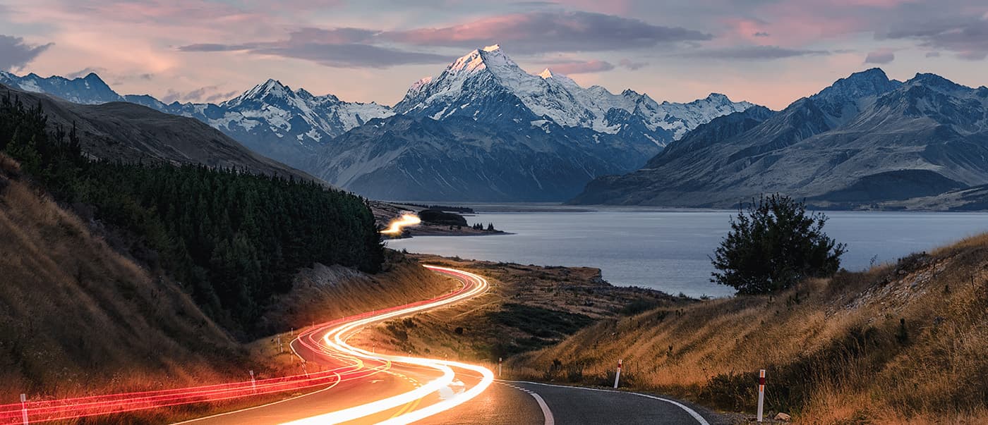 Road to Mt Cook in New Zealand during sunset with traffic causing light trails leading to the mountain. Road to Mt Cook in New Zealand during sunset with traffic causing light trails leading to the mountain.