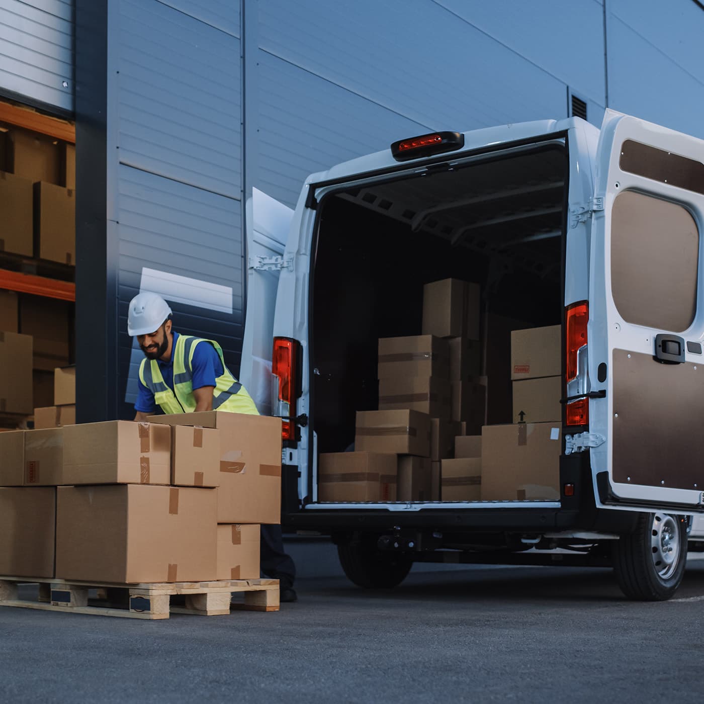 A delivery worker loading a delivery truck with goods ready for delivery to a customer. A delivery worker loading a delivery truck with goods ready for delivery to a customer.