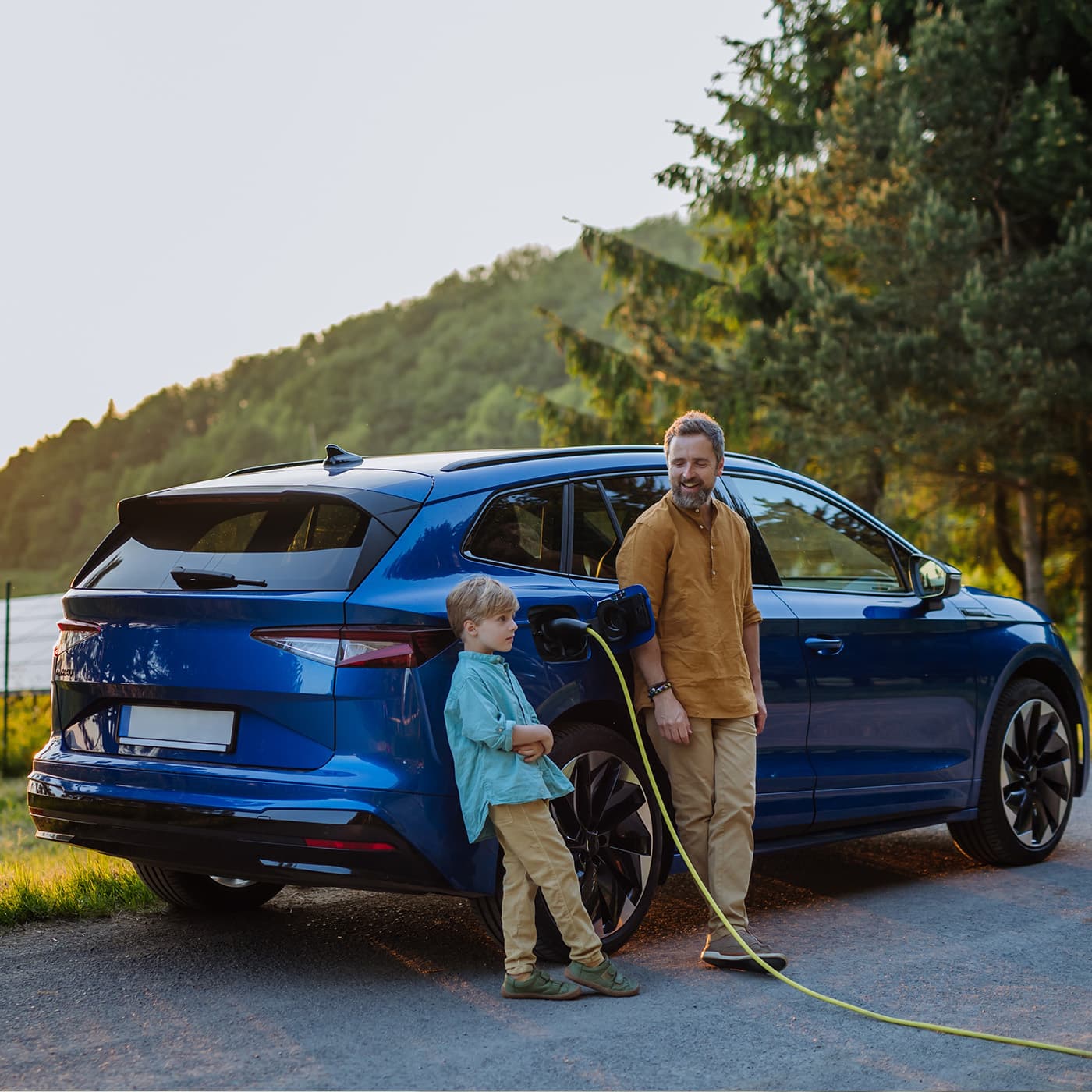 Father and his son charging electric car during their trip Father and his son charging electric car during their trip