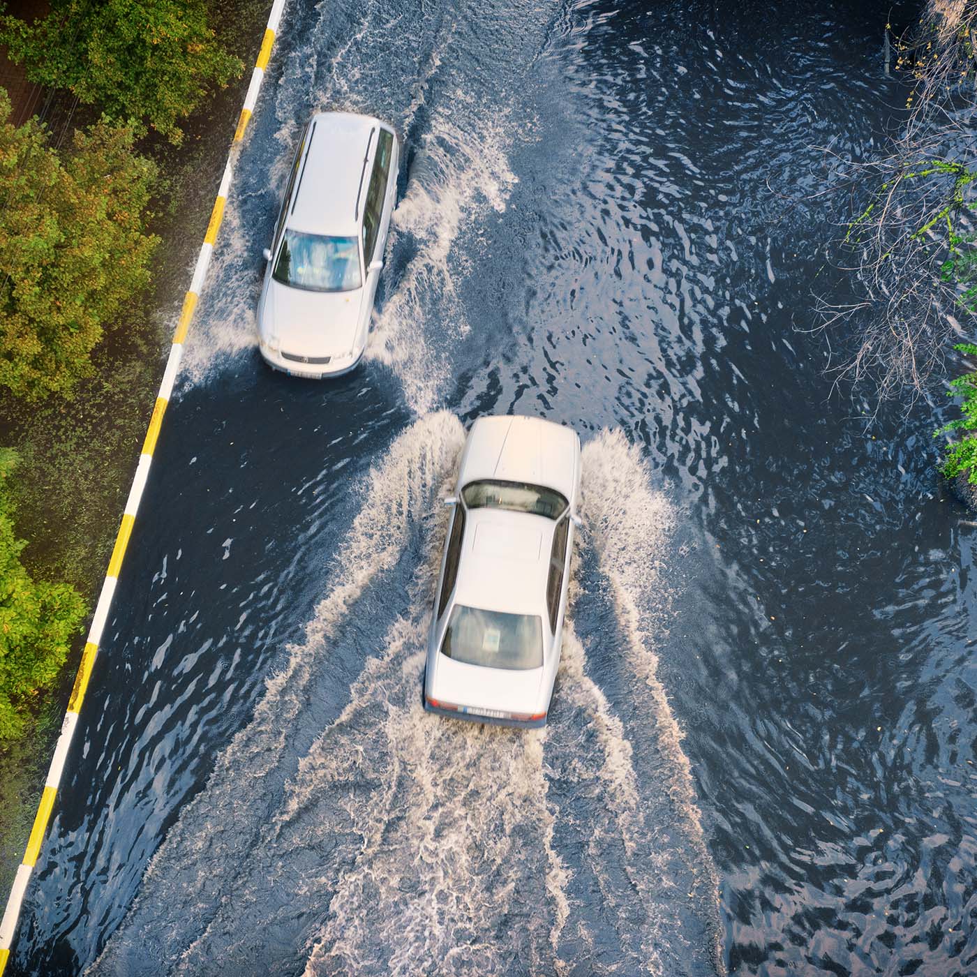 Two cars are moving on a flooded street after heavy rain. Two cars are moving on a flooded street after heavy rain.
