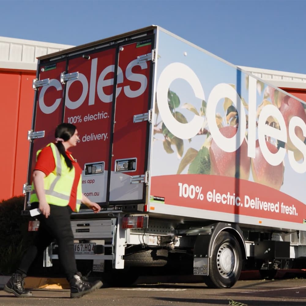A Coles staff member walking by Sparky, the electric delivery van. A Coles staff member walking by Sparky, the electric delivery van.