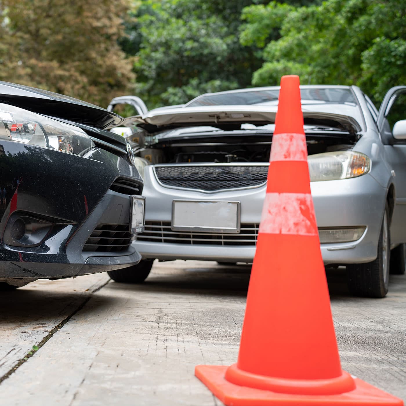 Close up view of two cars that have collided with a safety traffic cone in the foreground. Close up view of two cars that have collided with a safety traffic cone in the foreground.